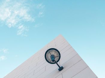 Low angle view of lighting equipment on wall of building against blue sky