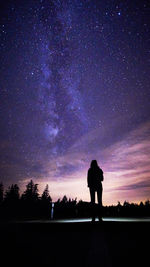 Silhouette woman standing against star field at night