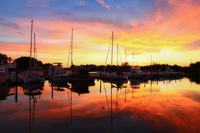 Boats moored at harbor during sunset