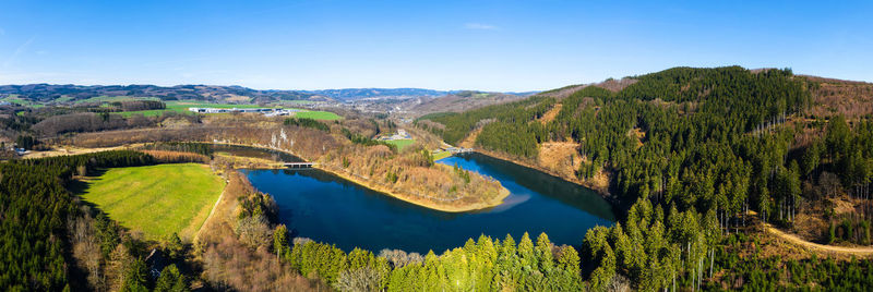 Scenic view of trees and mountains against blue sky