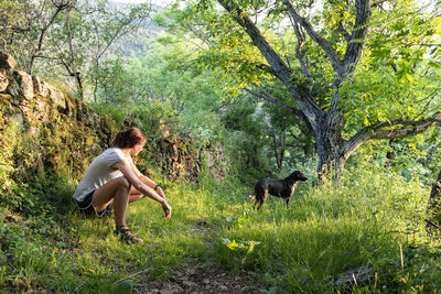 Woman petting and playing with her dog in a forest.