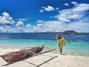 Woman standing on beach against sky