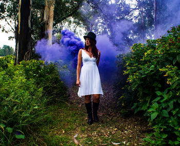 Full length portrait of young woman casting purple mist