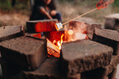 Close-up of man preparing fire on wood