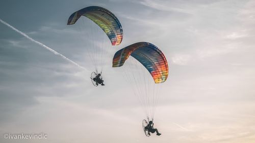 Low angle view of person paragliding against sky