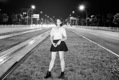 Portrait of young woman standing on railroad track at night