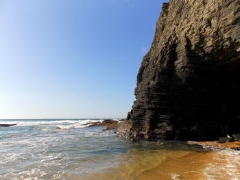 Rock formation on beach against clear sky