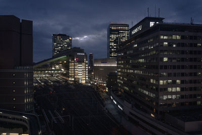 Illuminated buildings in city against sky at dusk