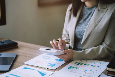 Midsection of businesswoman working on table