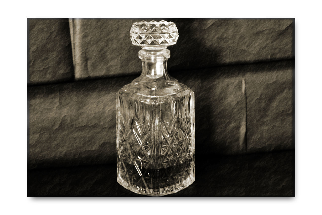 bottle, indoors, glass - material, container, no people, transparent, close-up, transfer print, table, perfume, auto post production filter, still life, nature, perfume sprayer, single object, wealth, elegance, wood - material, fragility, vulnerability, luxury