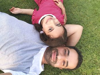 Directly above portrait of man lying down with daughter on grass