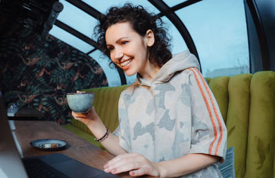 Portrait of smiling young woman sitting on table