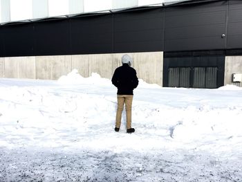 Rear view of man standing on snow covered field