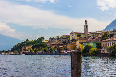 Buildings at waterfront against cloudy sky