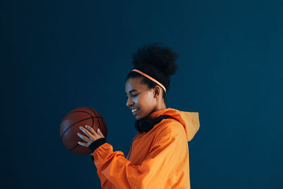 Side view of man playing with ball against blue background