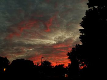 Low angle view of silhouette trees against dramatic sky