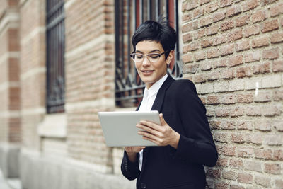 Portrait of content young businesswoman using tablet outdoors