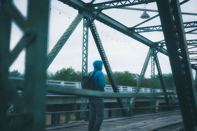 Young man backpacker in hoohie jacket 's walking cross the bridge