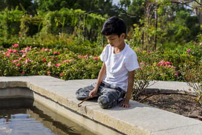 Side view of boy sitting on retaining wall