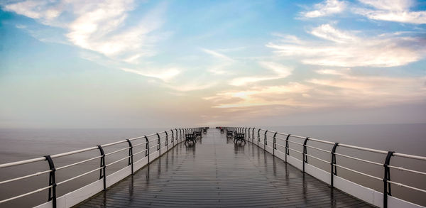 Pier over sea against sky during sunset