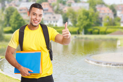 Portrait of smiling young man standing on lake