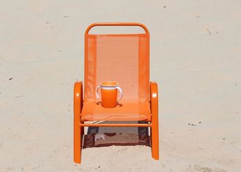 Orange cup and chair at beach during sunny day