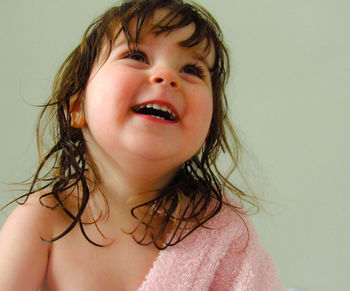 Close-up portrait of a smiling young woman against wall