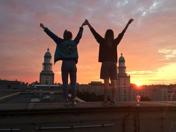 Women standing on roof wall against dramatic sky