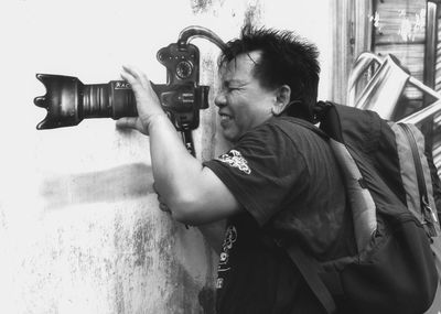 Optical illusion image of man looking through camera on wall