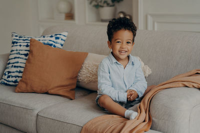 Portrait of boy sitting on sofa at home