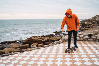 Full length of man standing on skateboard sky