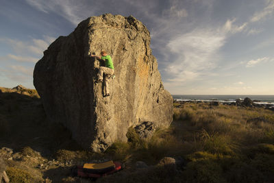 Man climbing rock against sky