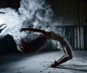 Full length of woman powder dancing in abandoned house