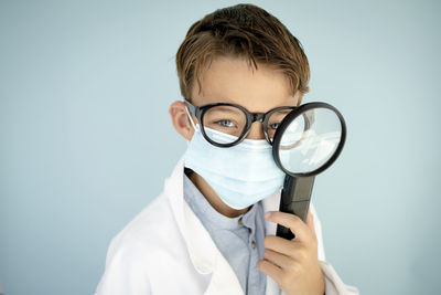 Cropped hand holding magnifying glass against white background