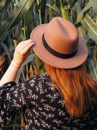 Rear view of woman wearing hat standing by plants