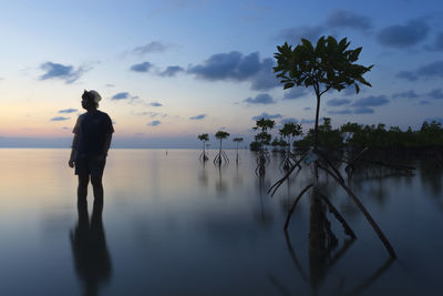 Silhouette man standing by sea against sky during sunset