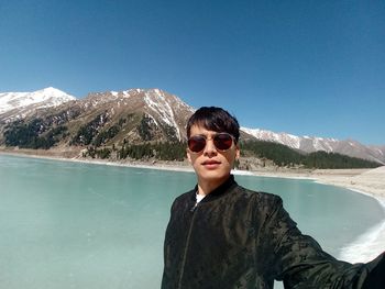 Portrait of man in sunglasses standing against sea