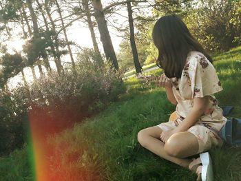 Young woman sitting on tree trunk