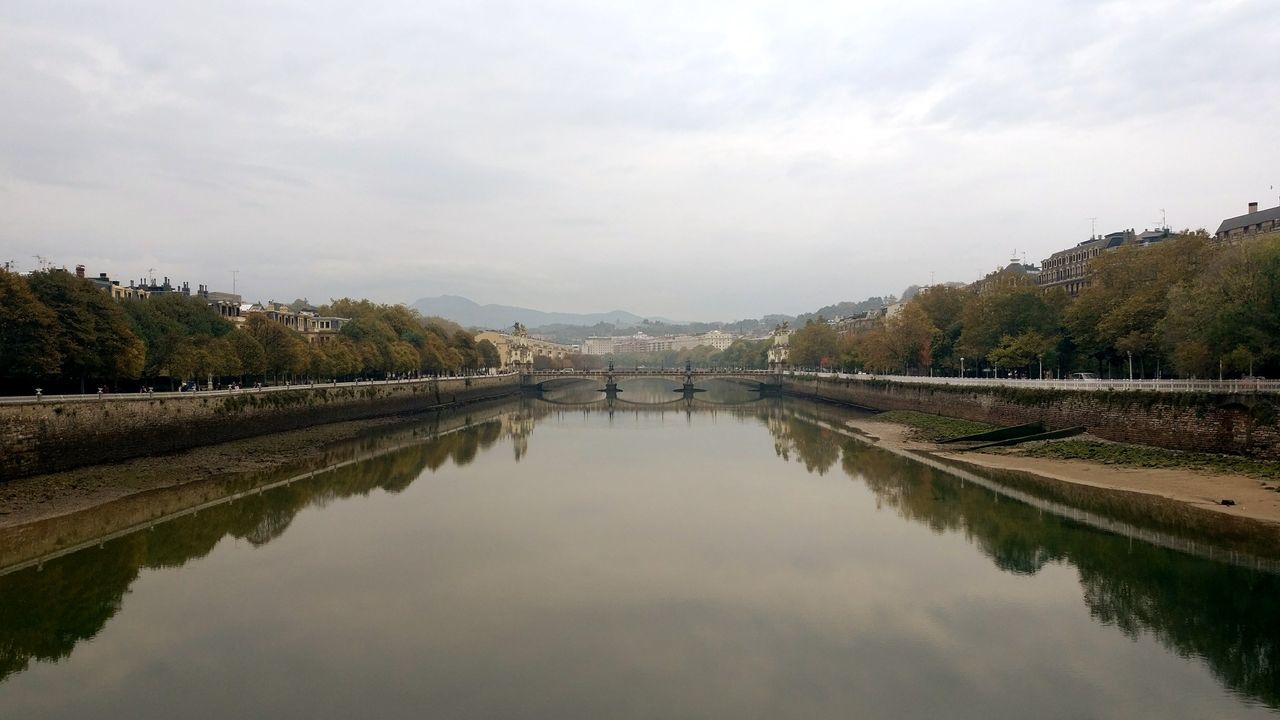 water, reflection, connection, bridge - man made structure, mountain, sky, river, scenics, tranquil scene, tree, cloud - sky, nature, waterfront, tranquility, architecture, outdoors, built structure, beauty in nature, no people, day, mountain range