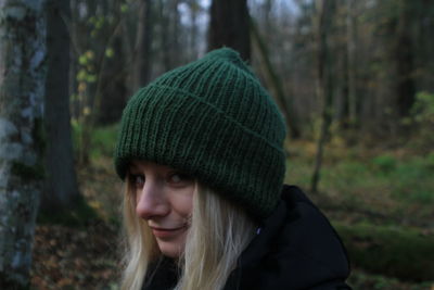 Portrait of woman wearing knit hat standing in forest