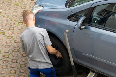 Rear view of man repairing car 