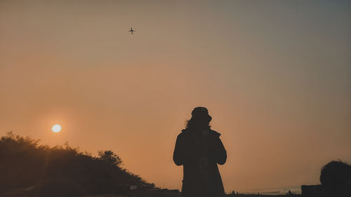 Silhouette man standing against sky during sunset