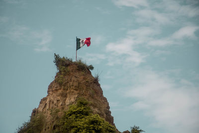 Low angle view of flag on rock against sky