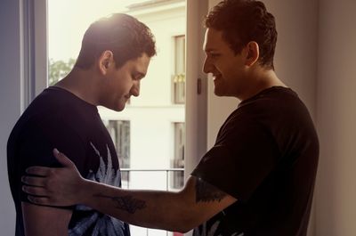 Side view of twin brothers standing at home