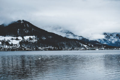 Scenic view of sea by snowcapped mountain against sky