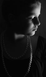 Close-up of girl looking away against black background