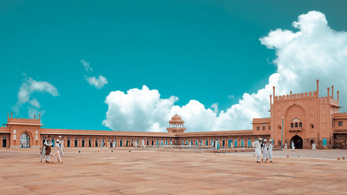 People at mosque against blue sky