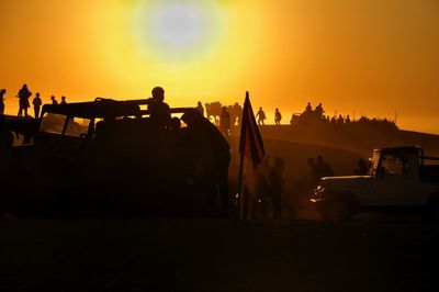 Silhouette people against orange sky during sunset