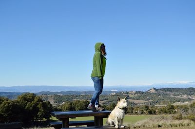 Rear view of woman with dog standing on mountain