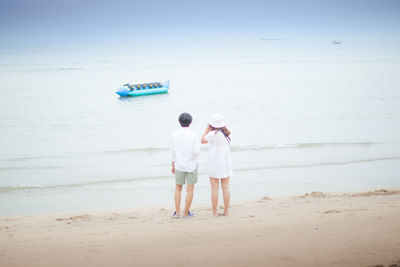 Rear view of couple standing on beach